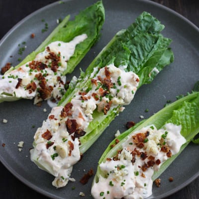 A blue plate with wedges of romaine topped with buffalo blue cheese dressing, crumbled bacon.