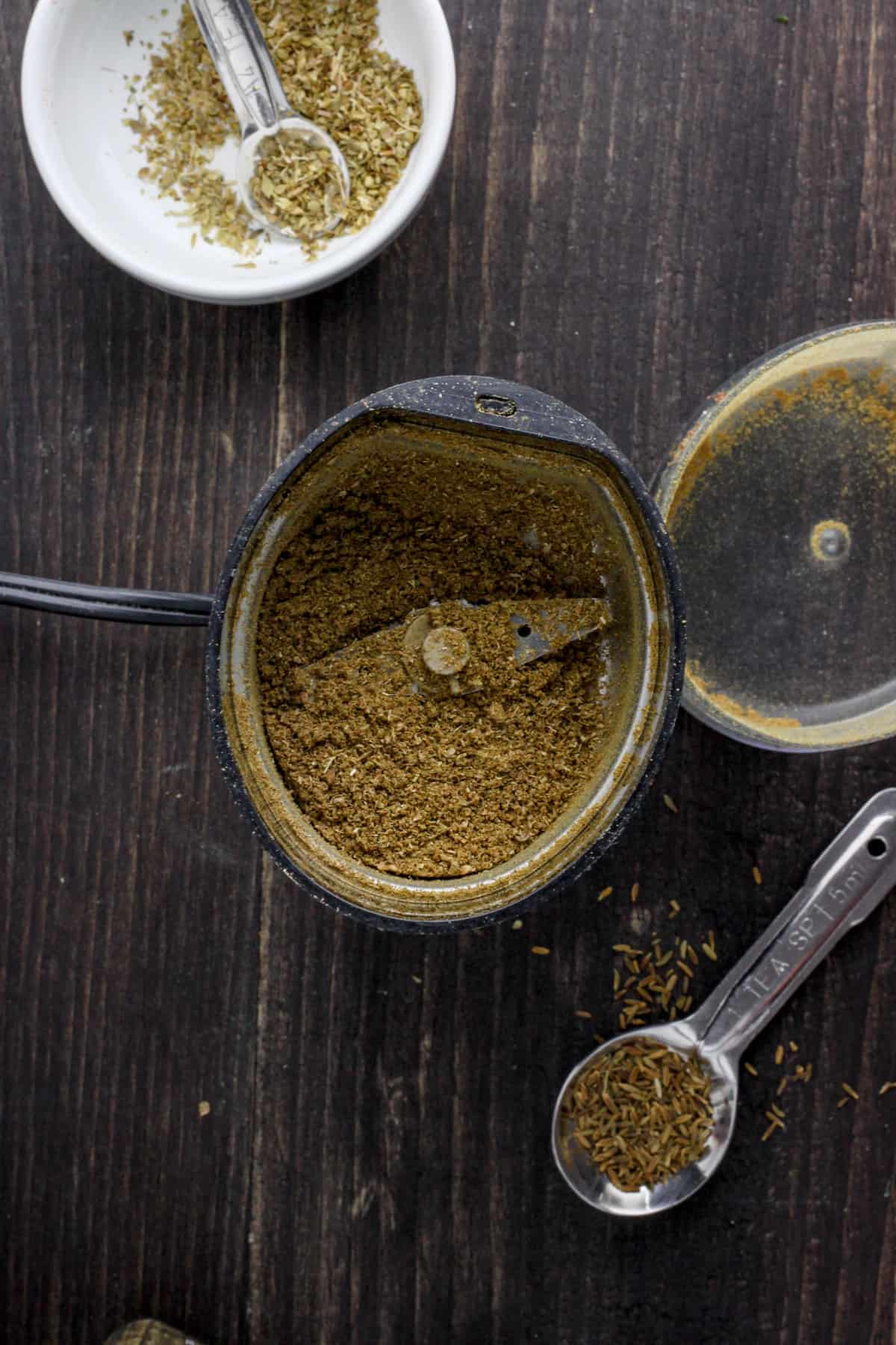 A black spice grinder with pulverized spices inside.