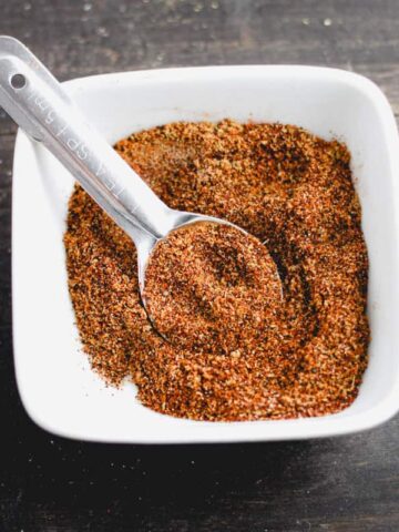 A white bowl with chicken taco seasoning and a teaspoon.
