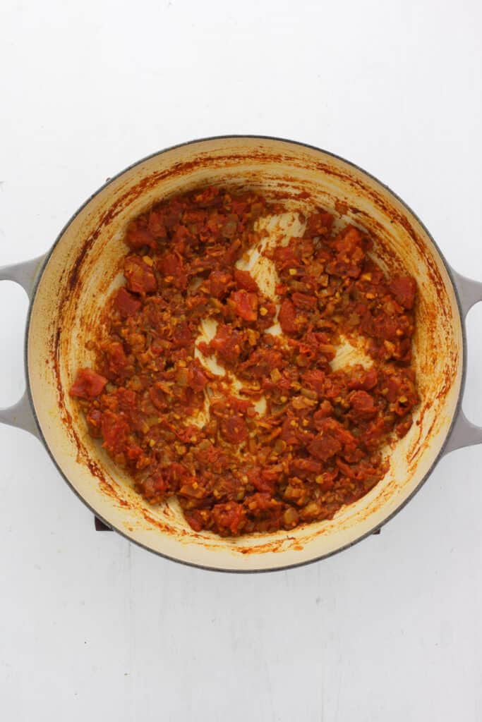 A braiser pan with onions and tomatoes reduced to a jam consistency.