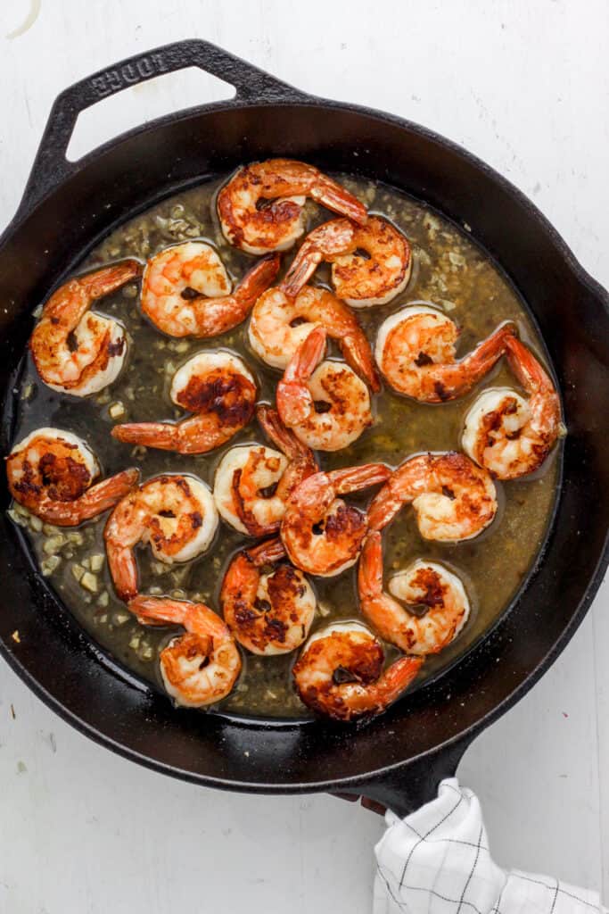 skillet with seared shrimp and a white wine sauce.