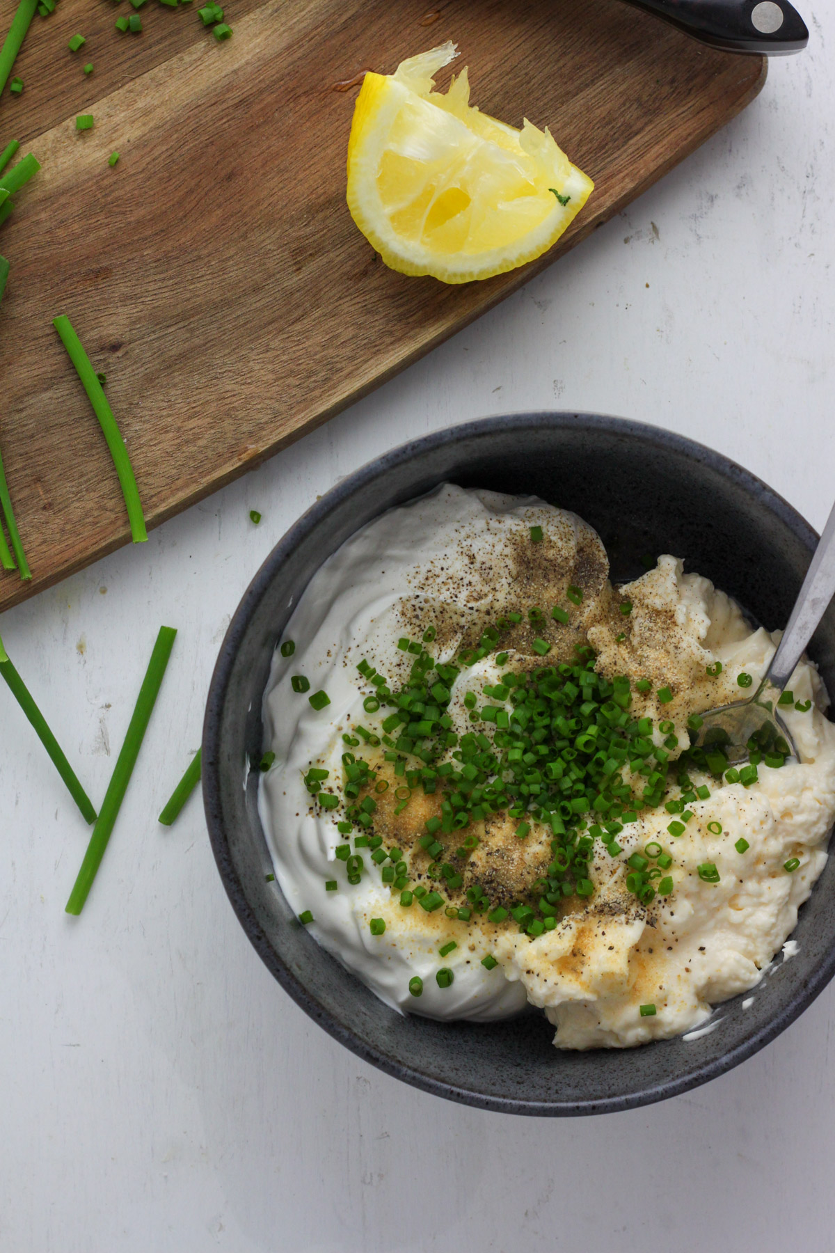 A blue bowl with sour cream and onion dip unstirred.