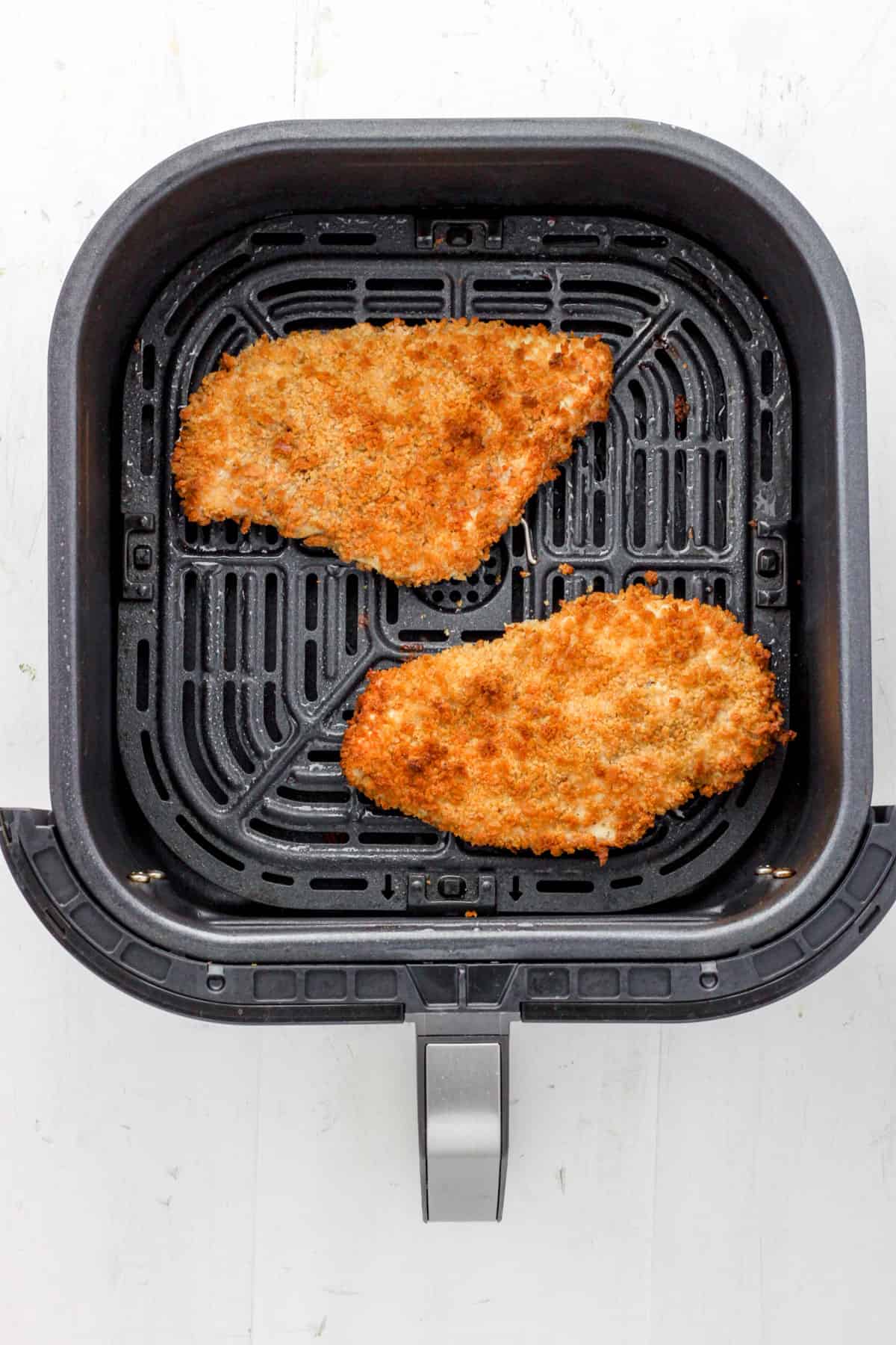 An air fryer basket with golden brown chicken katsu.