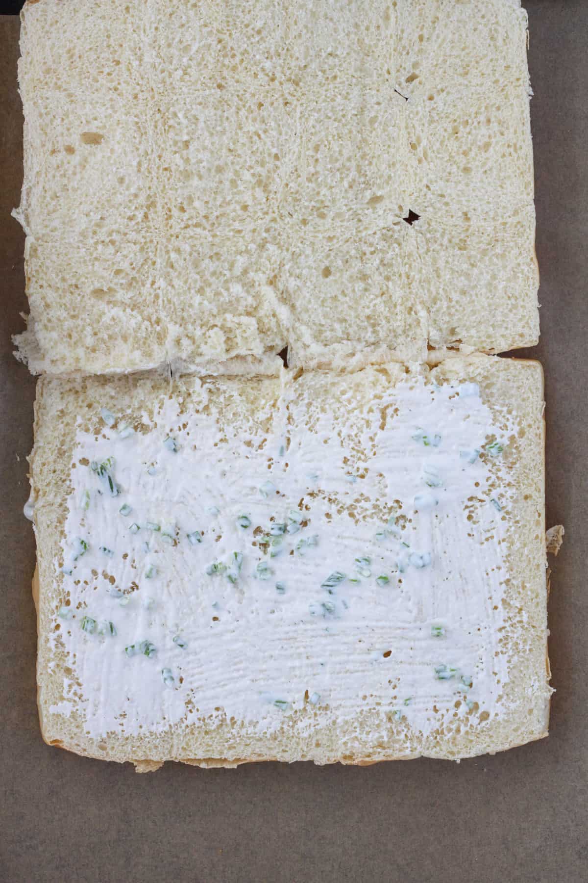 Sweet Hawaiian rolls cut in half and placed on a parchment lined baking sheet.