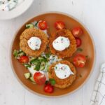 A plate of chickpea patties topped with a lemon and herb yogurt sauce.