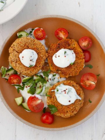 A plate of chickpea patties topped with a lemon and herb yogurt sauce.