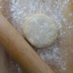 An all butter dough on a work surface with a rolling pin.