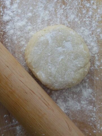 An all butter dough on a work surface with a rolling pin.