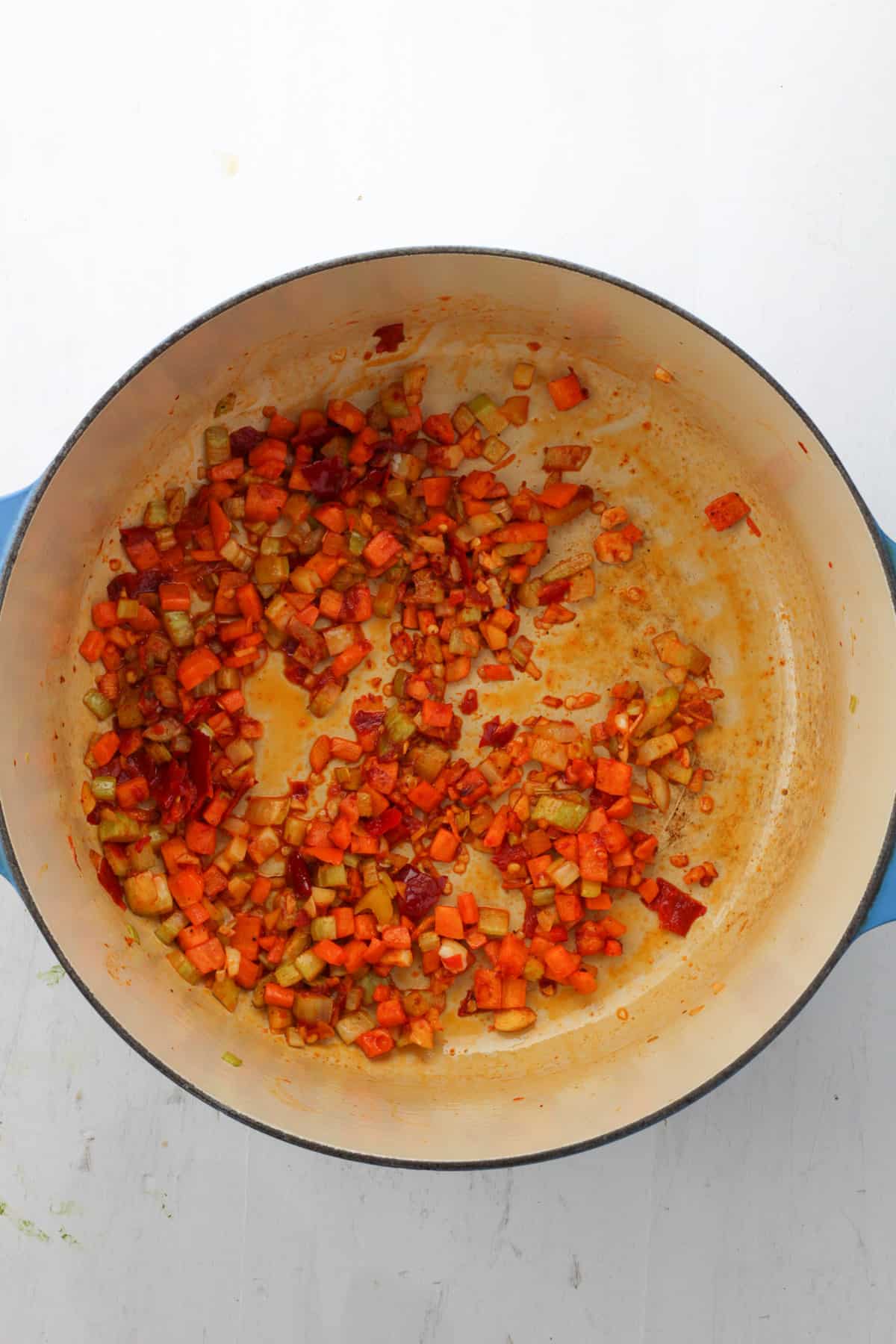 A Dutch oven with sautéed carrots, celery, garlic, Calabrian peppers and tomato paste.