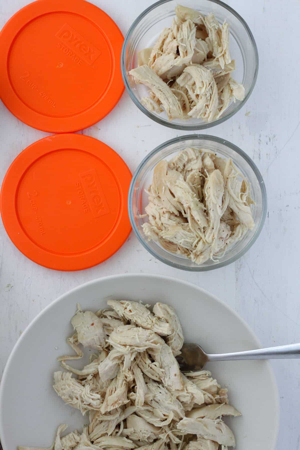 Dutch oven pulled chicken portioned into a containers for meal prep.