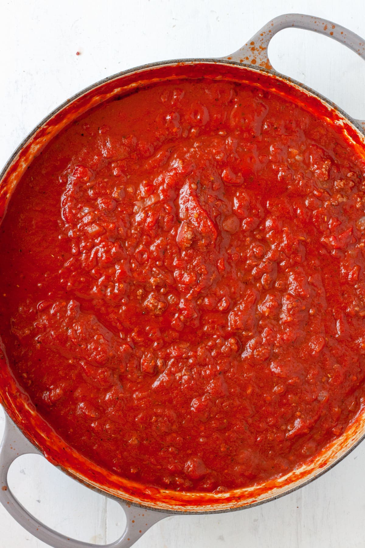 Tomato sauce cooking in a large skillet.