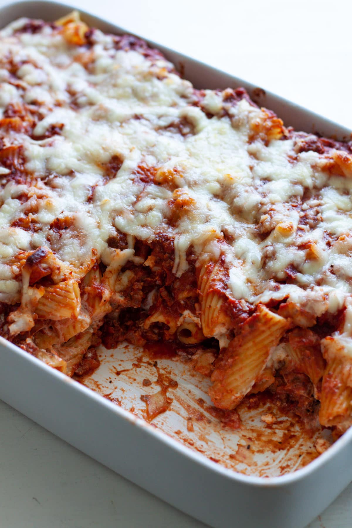 A baking dish with rigatoni al forno and a piece taken out of the pasta dish.