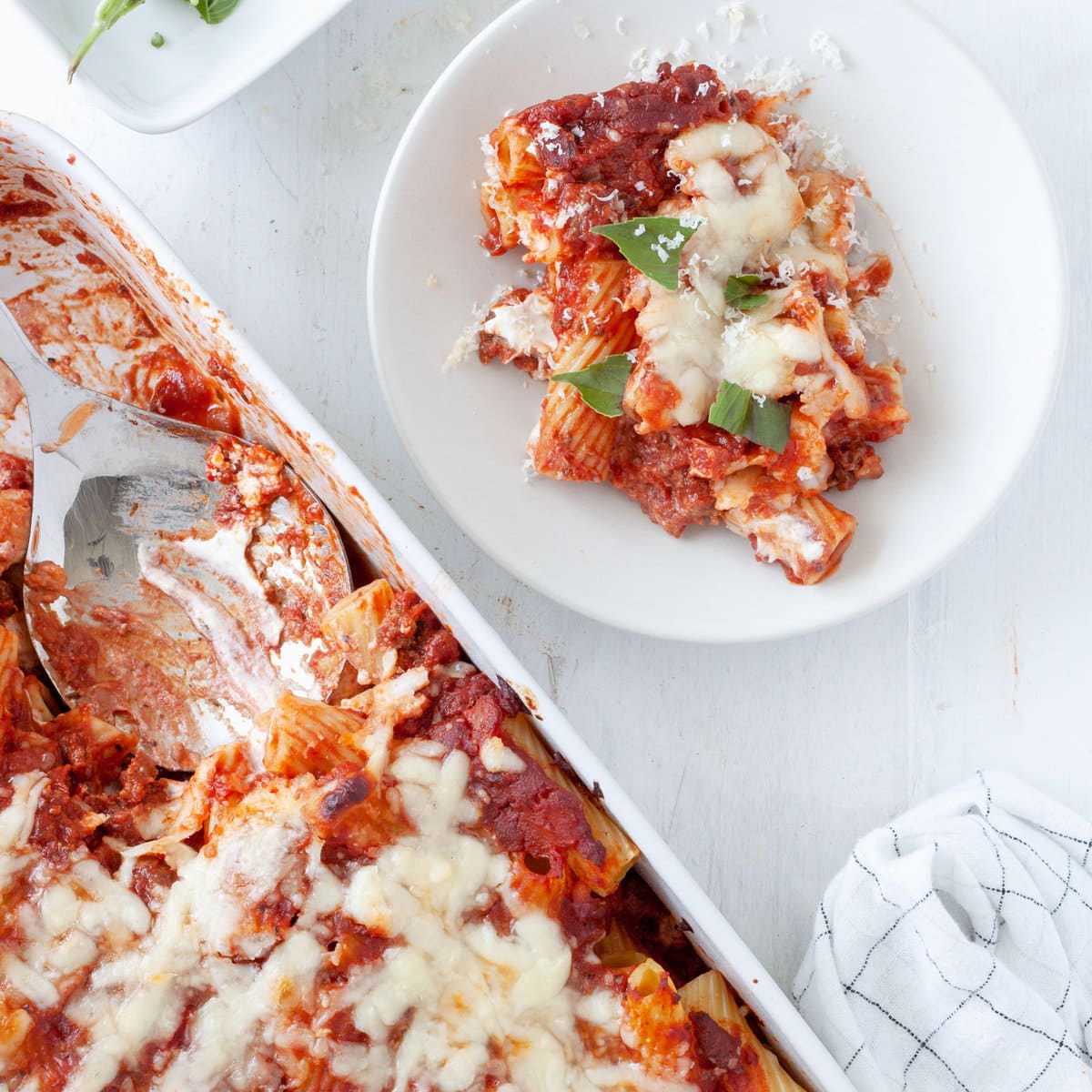 A scoop of rigatoni al forno taken out of a baking dish full of the baked pasta.