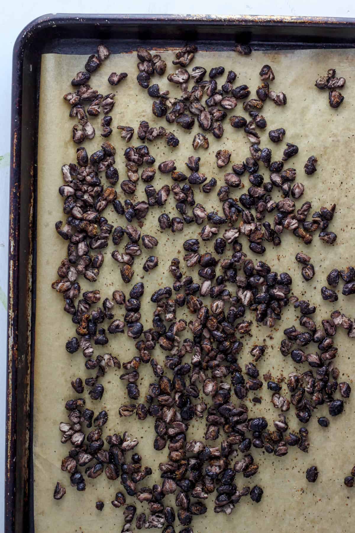 A baking sheet with parchment topped with crispy roasted black beans.