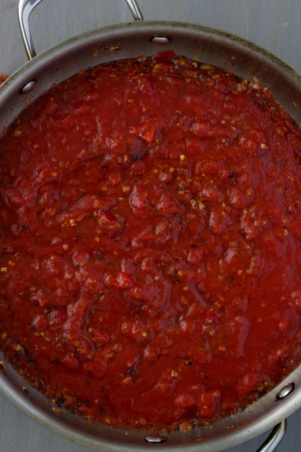 A large skillet with arrabiata sauce cooking.