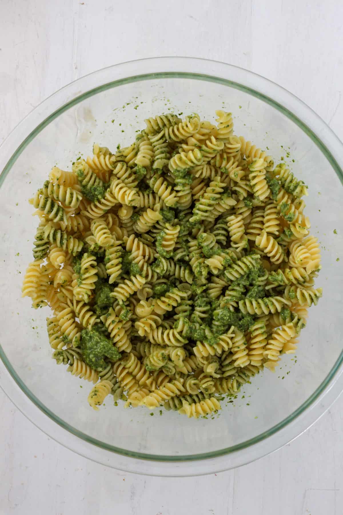 A large bowl with pasta and pesto mixed together.