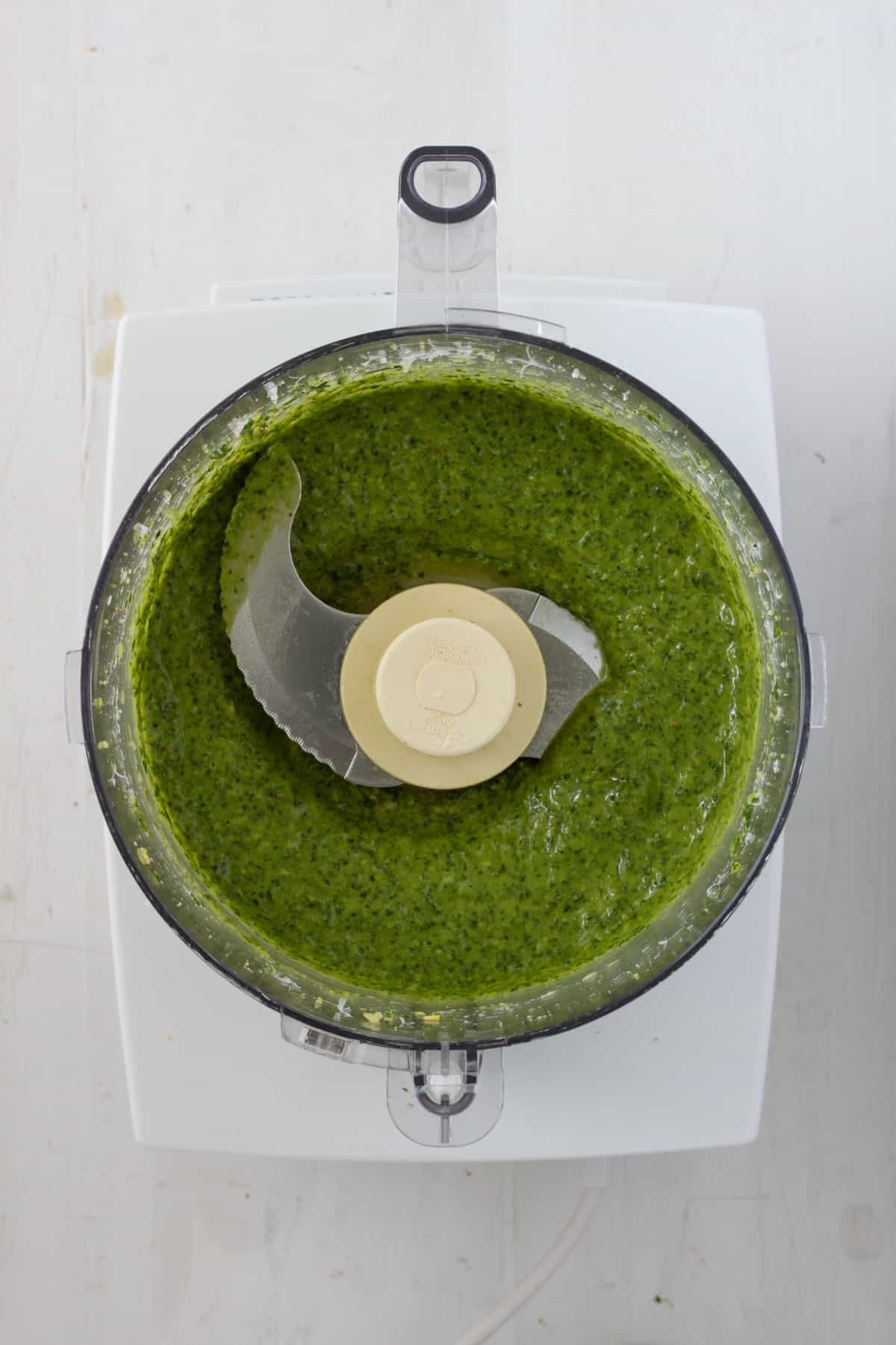 Creamy basil pesto in the base of a food processor.