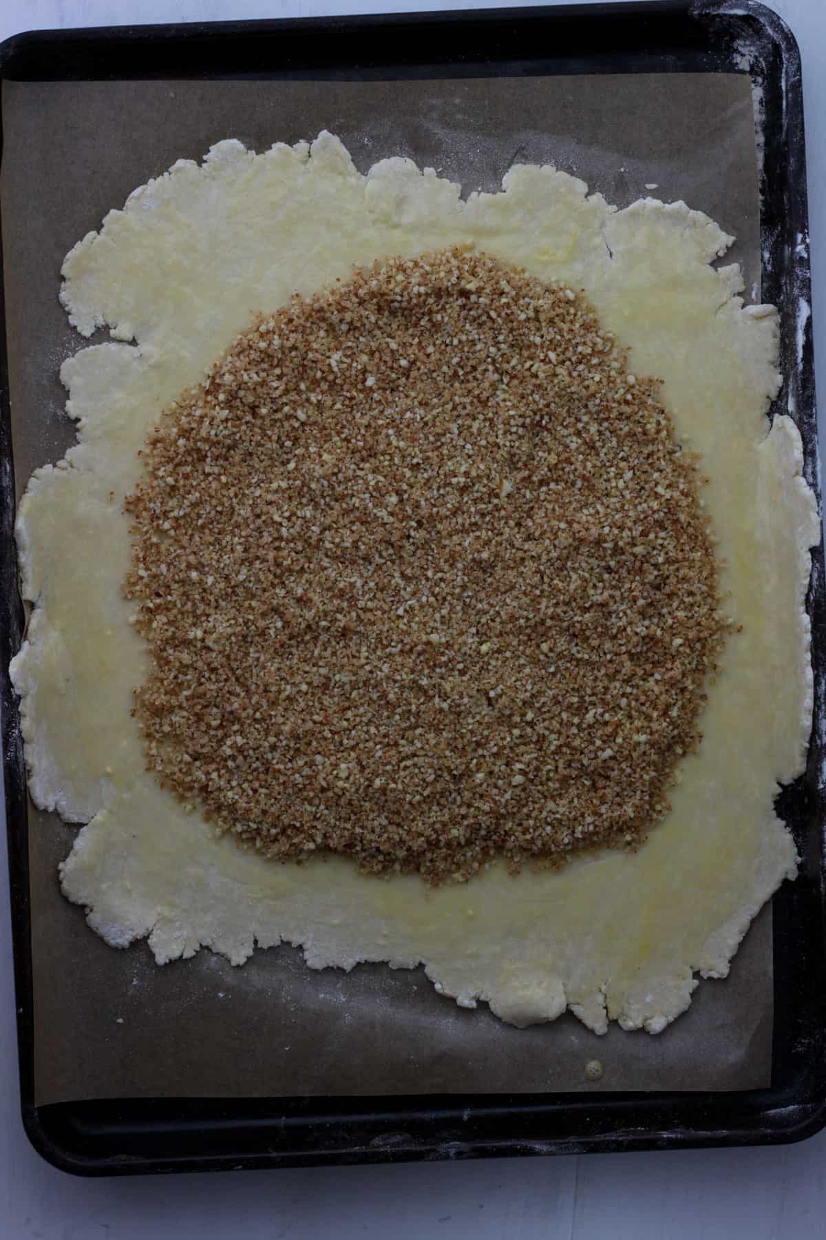 Pie crust rolled out thin and ground almonds and breadcrumbs in a thin layer on top.