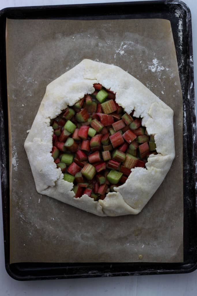 A rhubarb galette on a parchment lined baking sheet unbaked.