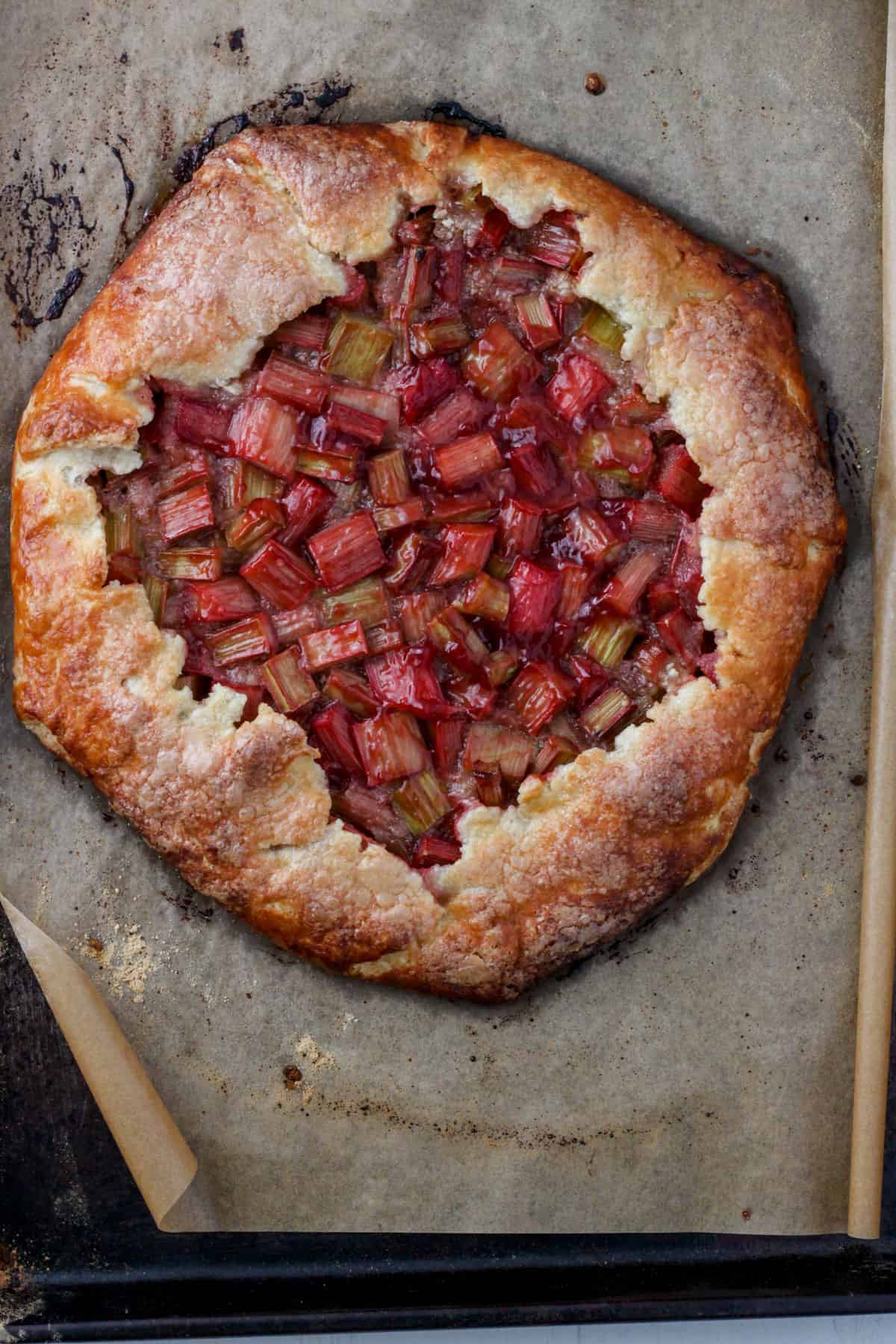 A baked rhubarb galette on a parchment lined baking sheet.