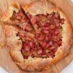 Rhubarb galette on a pizza peel with a slice cut away.