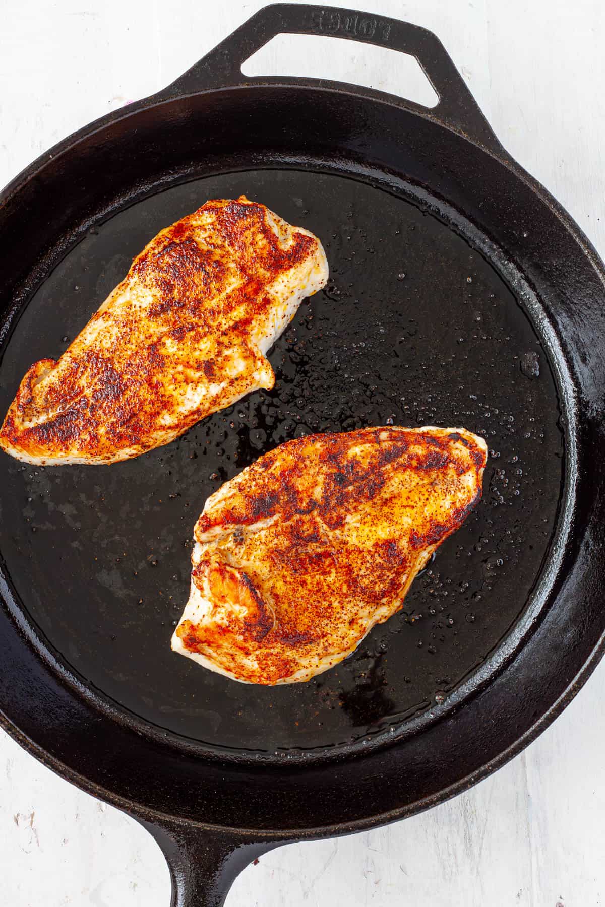Chicken breasts seared in a cast iron skillet.