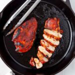 Barbecue chicken breasts in a cast iron skillet.
