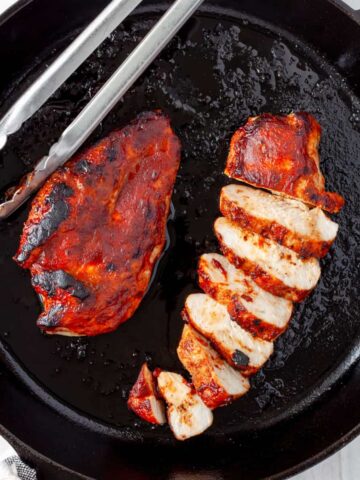 Barbecue chicken breasts in a cast iron skillet.