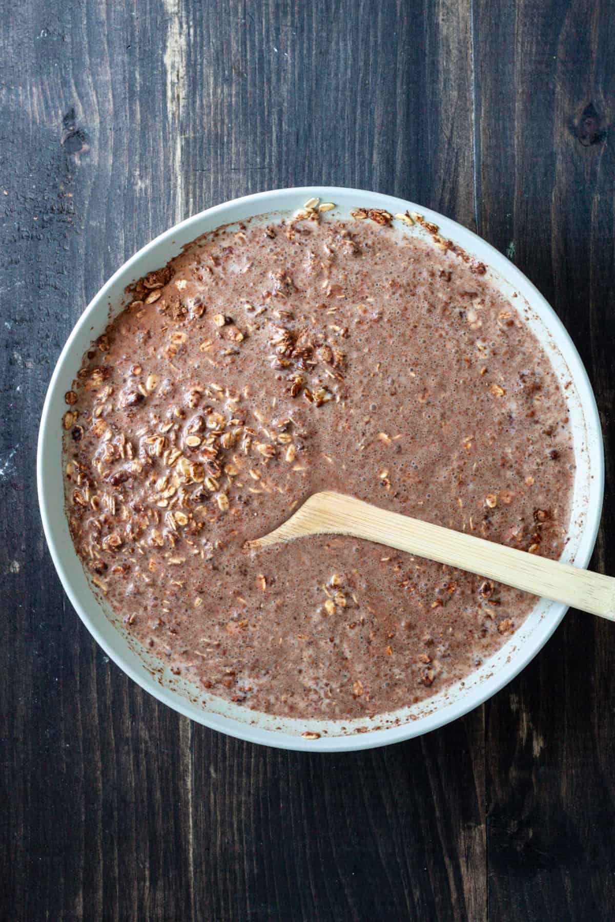 Chocolate baked oatmeal in a medium bowl getting stirred together.