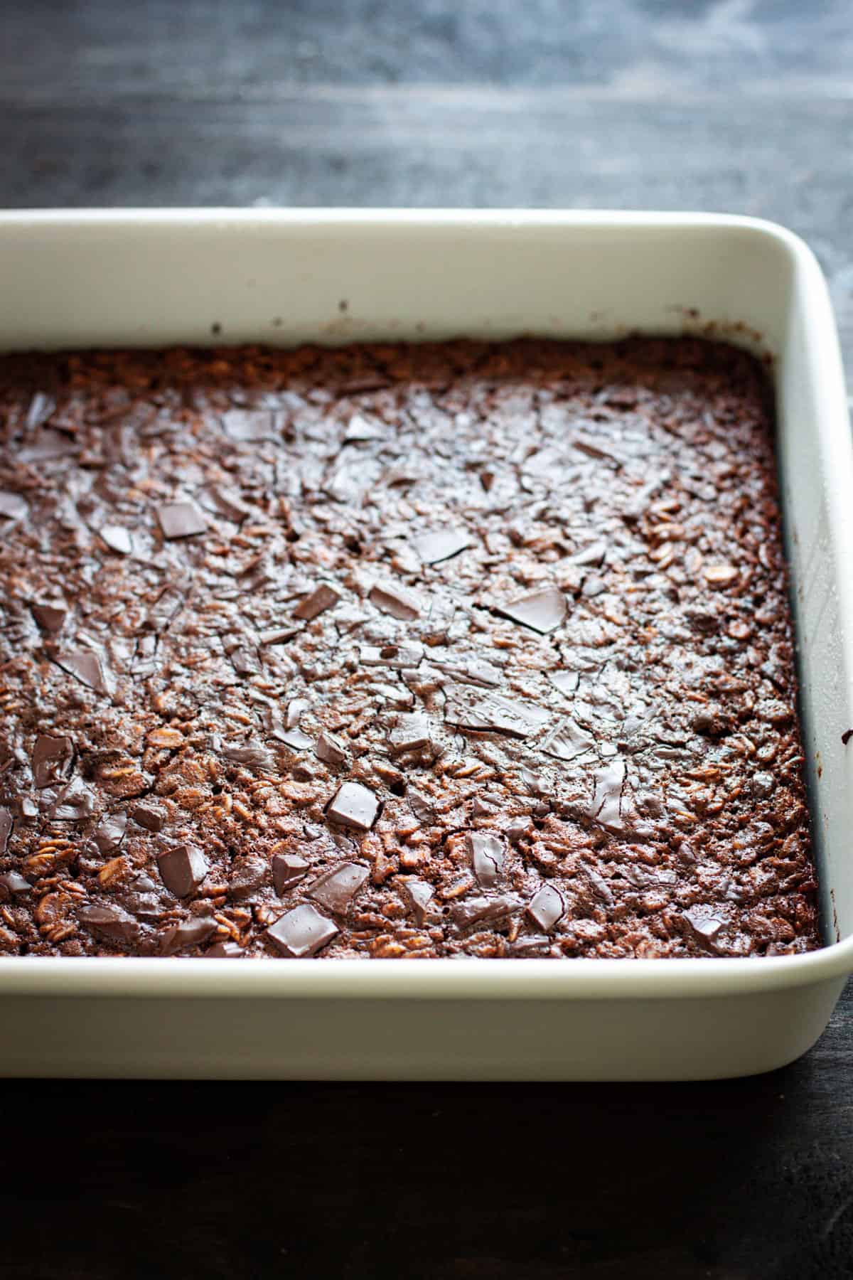 Chocolate baked oatmeal in a square baking dish on a dark table.