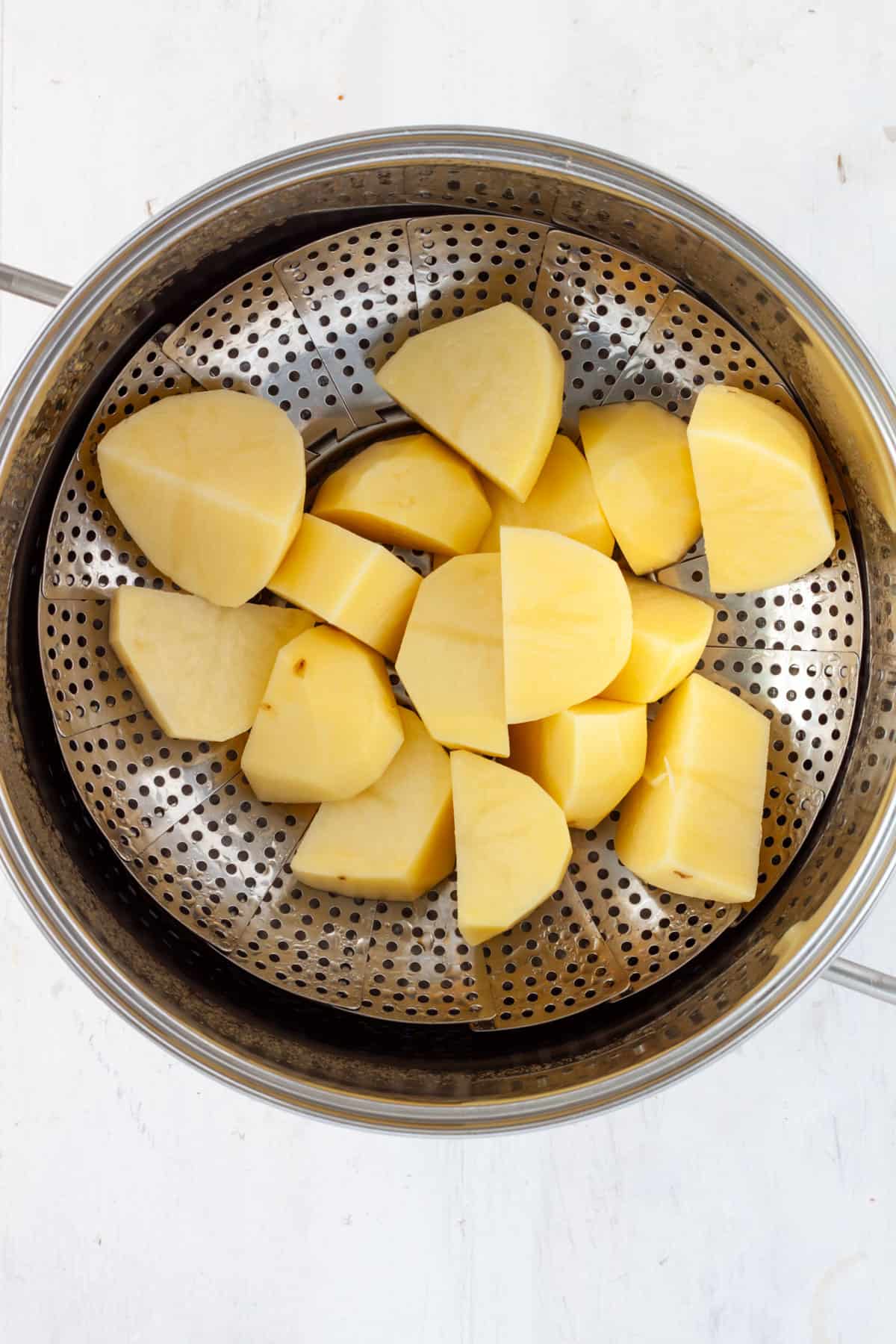Wedges of Yukon gold potatoes in a steamer basket set in a large pot.