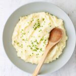 A bowl of Yukon gold mashed potatoes topped with chopped chives.