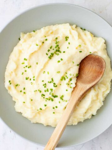 A bowl of Yukon gold mashed potatoes topped with chopped chives.