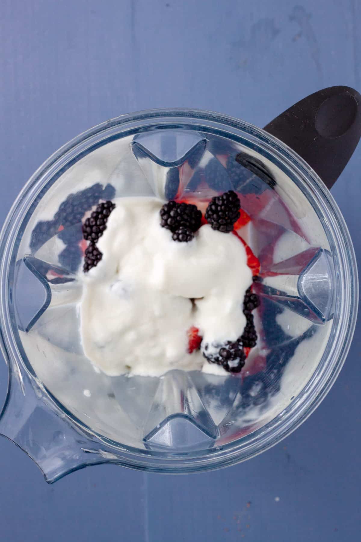 Berries, milk and yogurt in the base of a food processor.