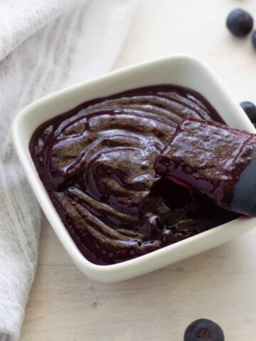 Blueberry BBQ Sauce in a small bowl with a pastry brush inside.