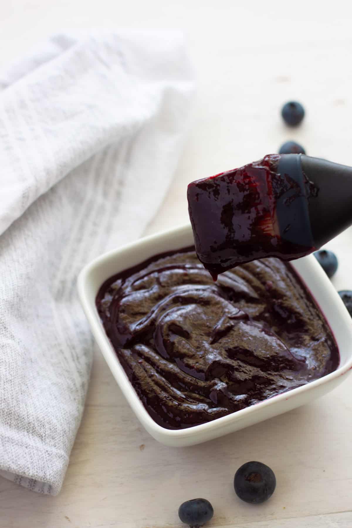 A brush and small dish of blueberry bbq sauce.