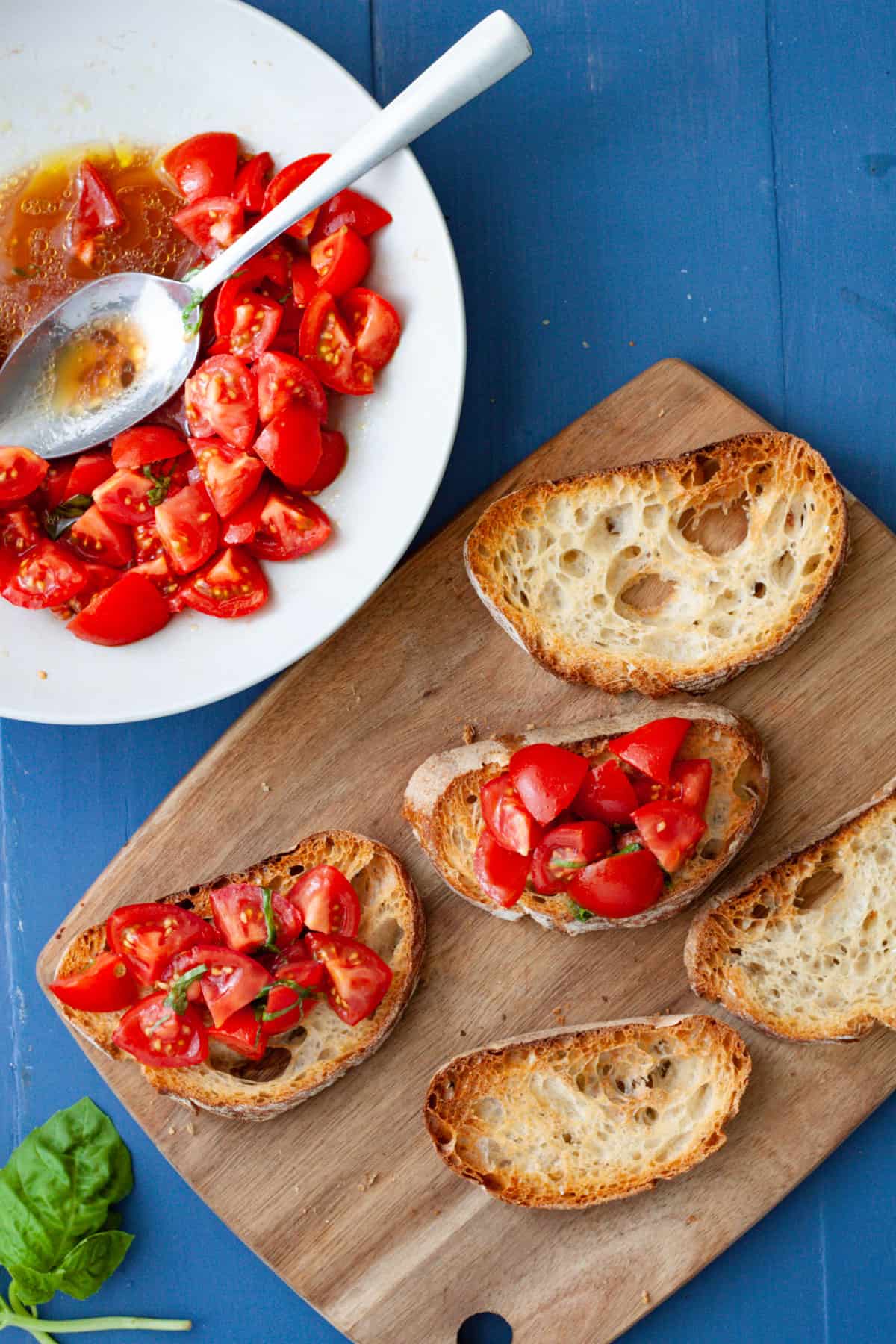 Bruschetta getting assembled on a cutting board.