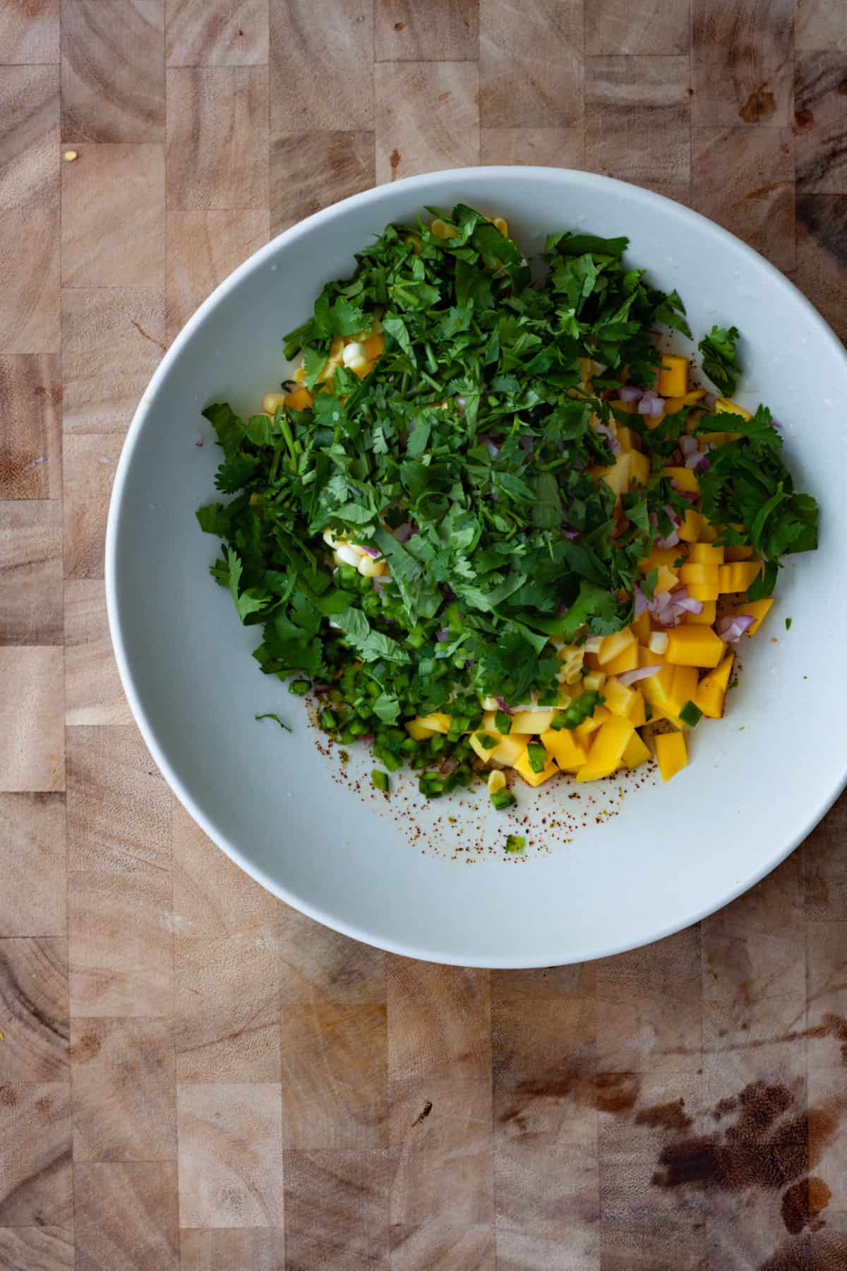 Corn, mango and cilantro in a medium mixing bowl as mango and corn salsa is getting assembled.