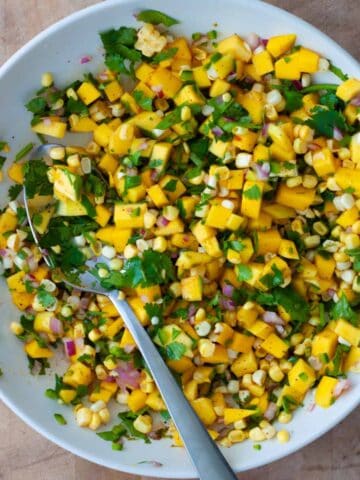 Mango and Corn Salsa in a medium bowl with a spoon.
