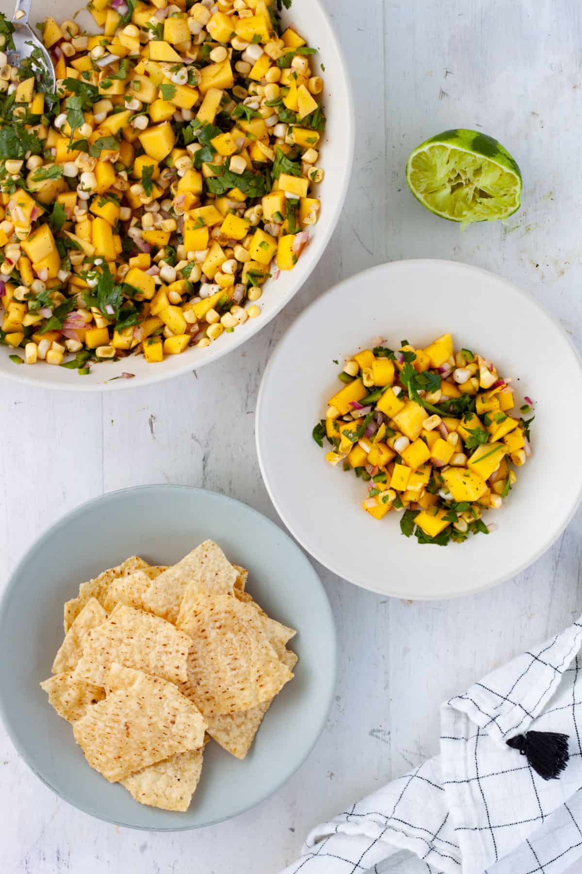 Mango and Corn Salsa in a large bowl with a smaller serving on the side and a small bowl of tortilla chips.