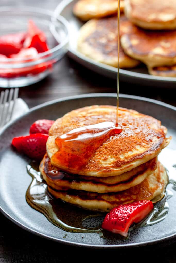 A light and fluffy stack of oat milk pancakes drizzled with maple syrup.