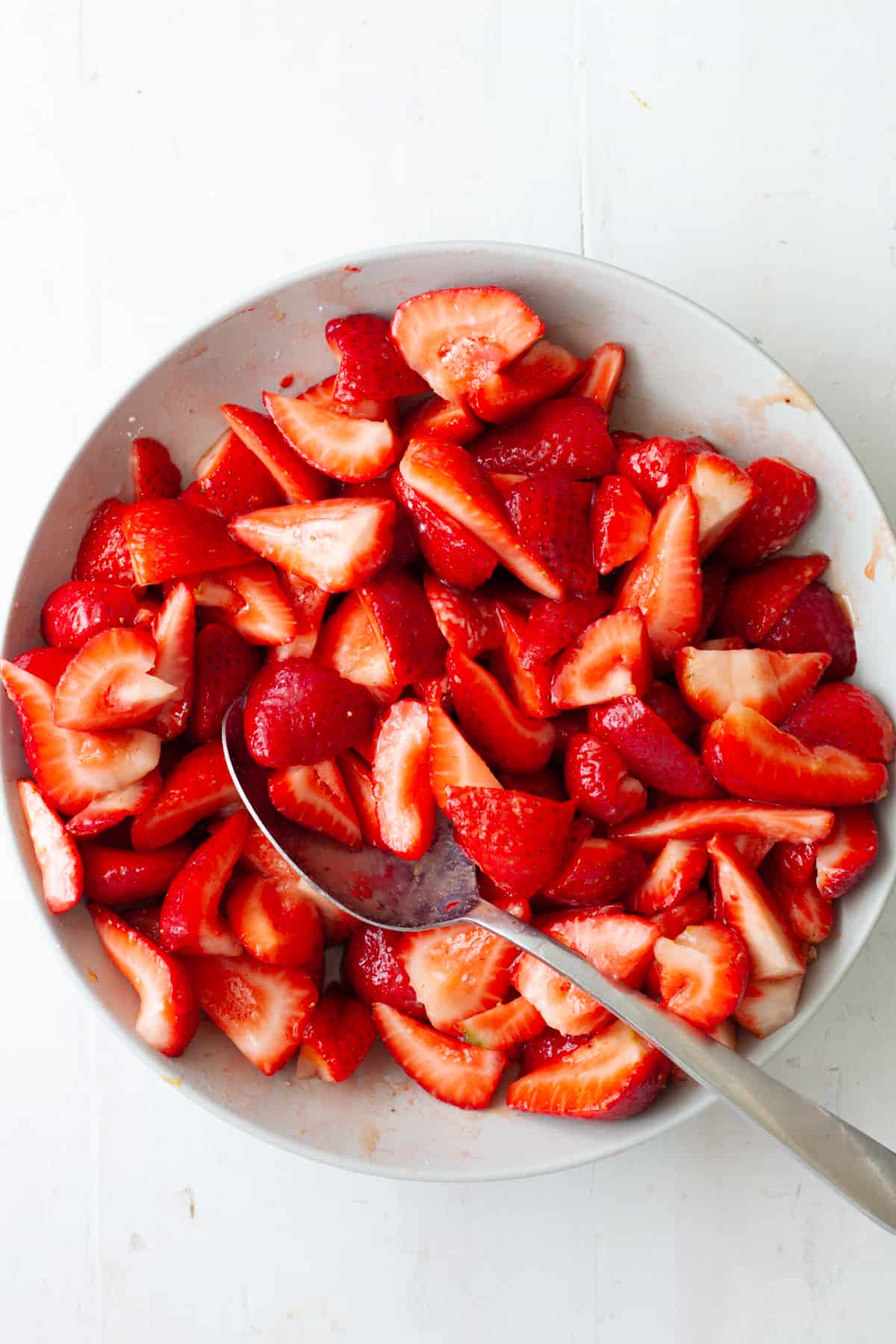 Strawberries mixed with sugar in a medium mixing bowl.