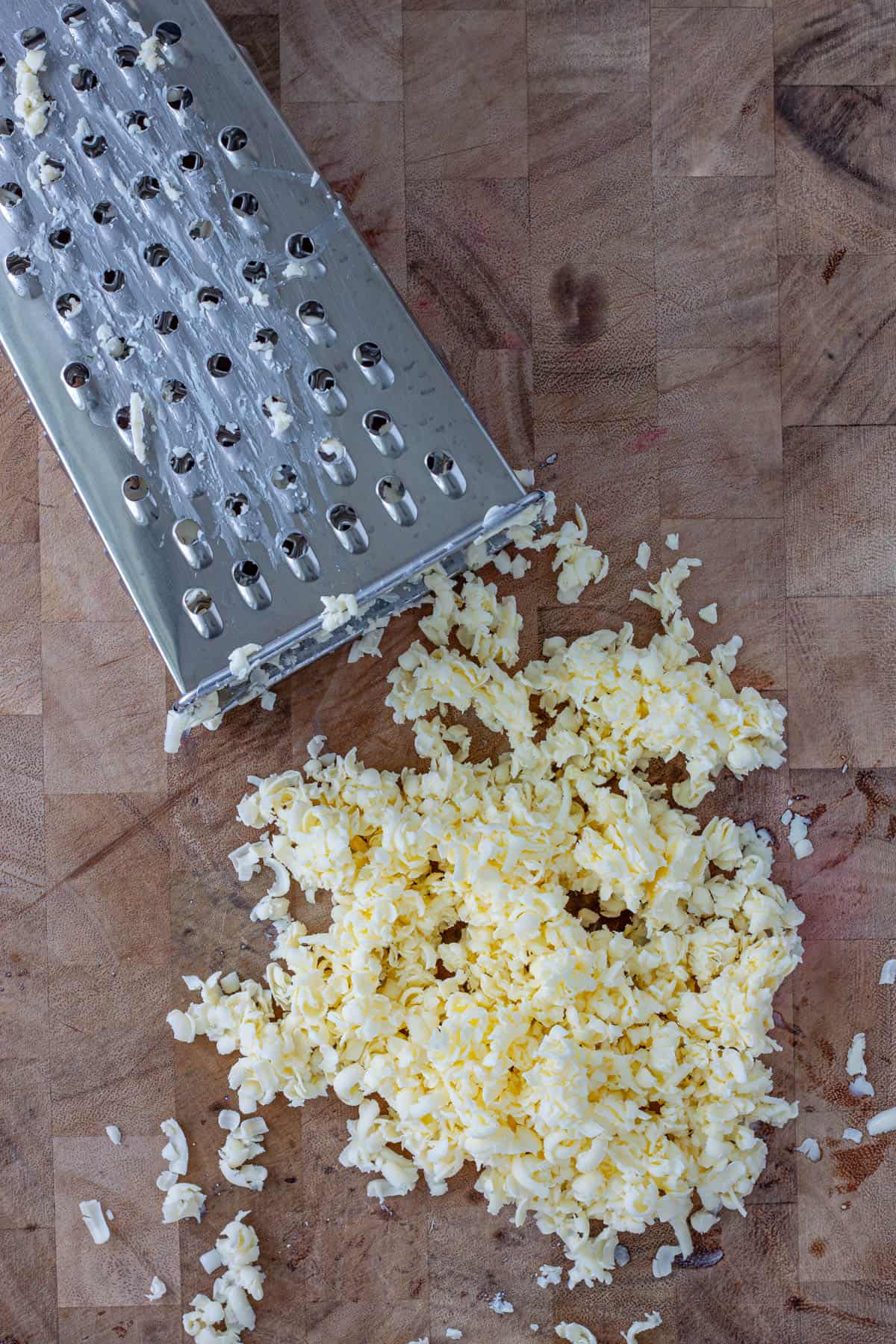 Butter grated with a box grater on a cutting board.