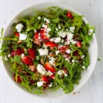 Strawberry and goat cheese salad in a white mixing bowl.