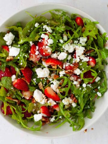Strawberry and goat cheese salad in a white mixing bowl.