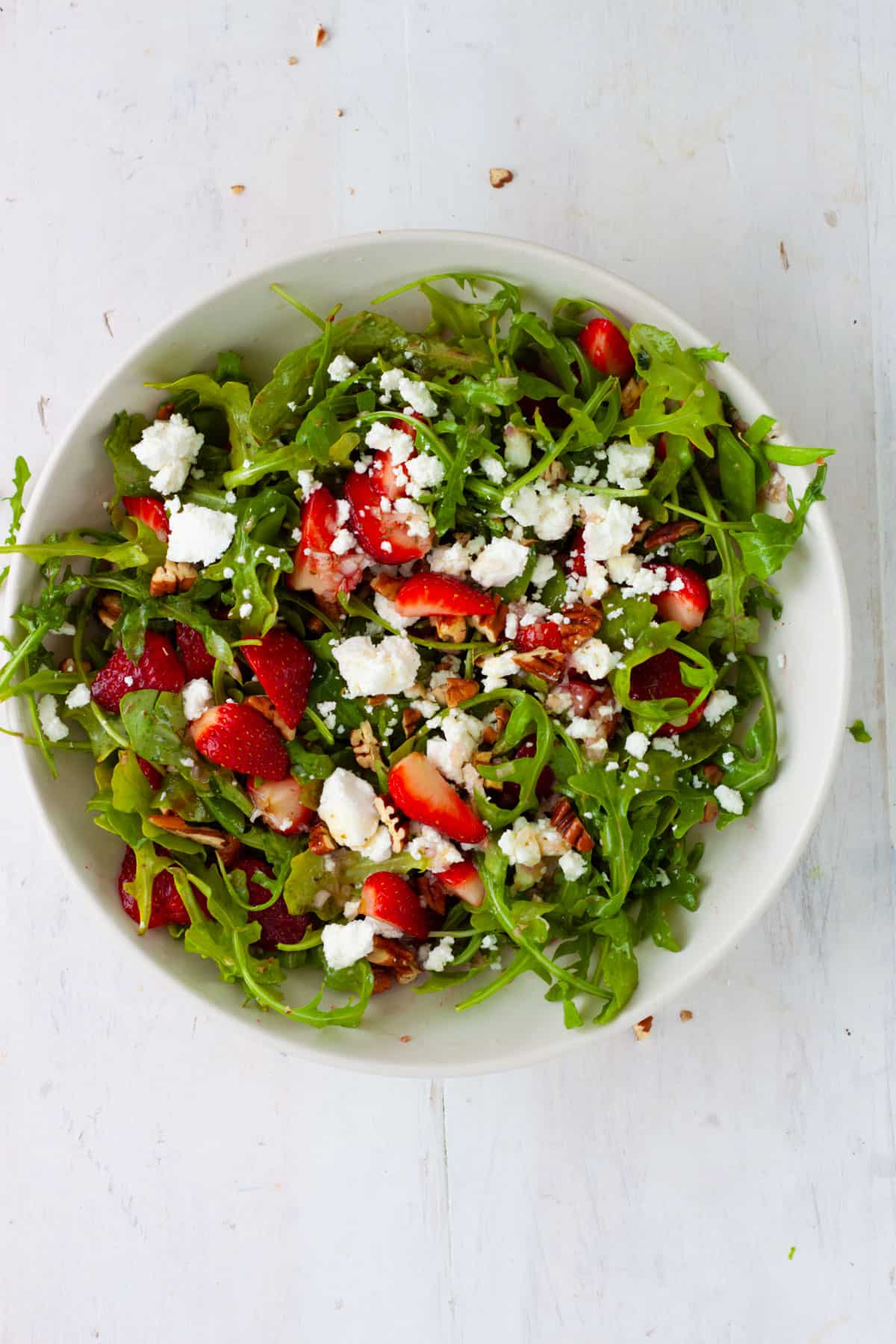 Strawberry and goat cheese salad in a white mixing bowl.