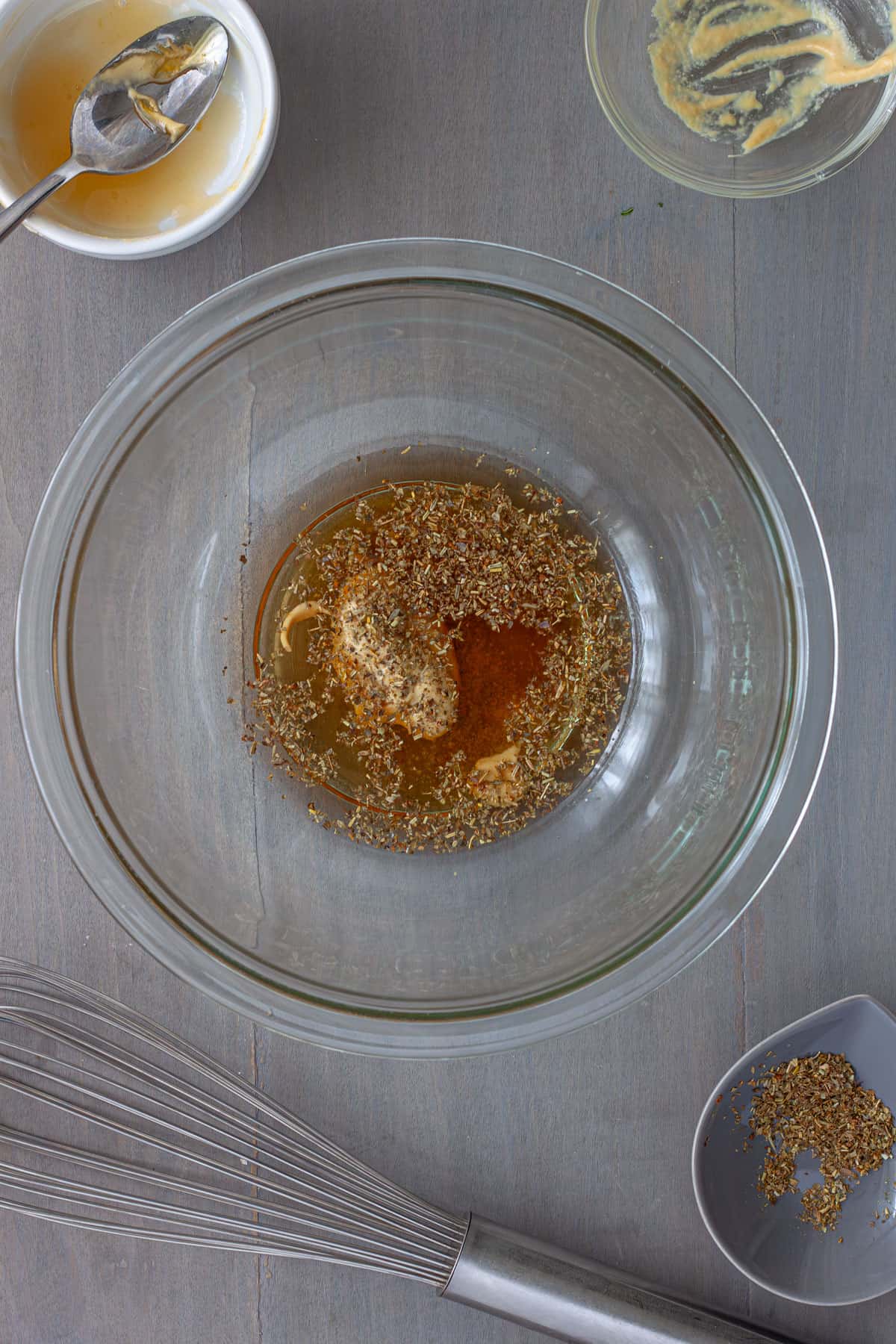 Ingredients for a white balsamic vinaigrette in a medium mixing bowl unmixed.