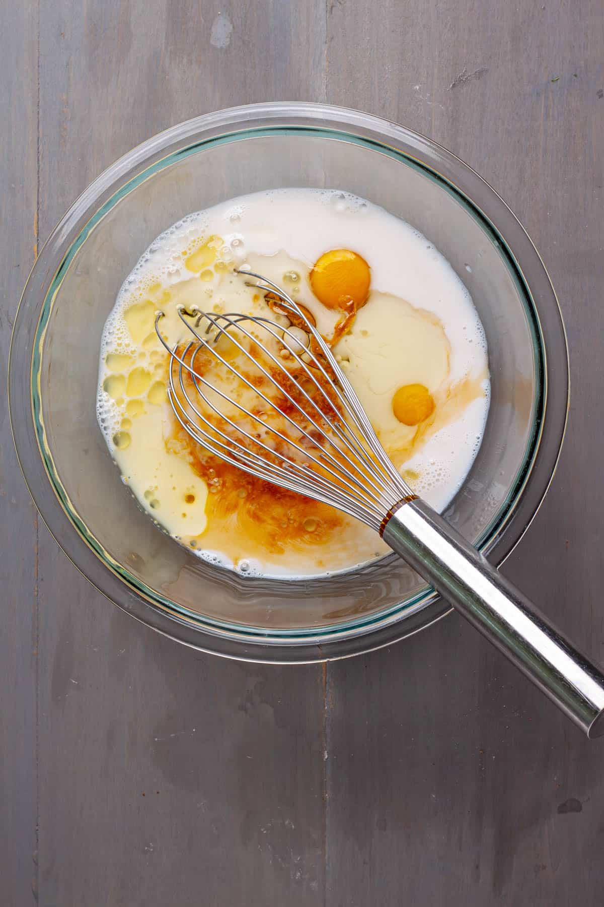 Wet ingredients for peanut butter baked oatmeal in a mixing bowl with a whisk.