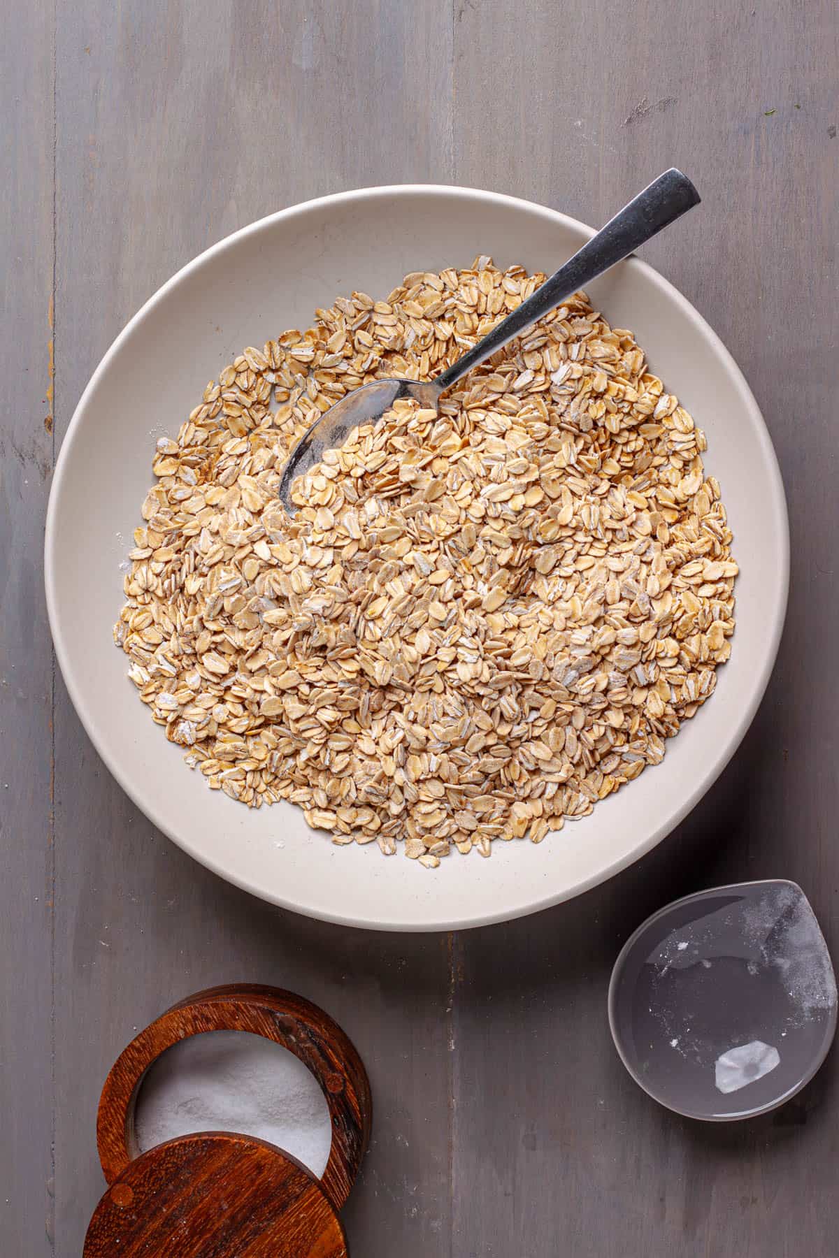 Dry ingredients for a peanut butter and jam baked oatmeal in a medium bowl with a spoon off to the side.