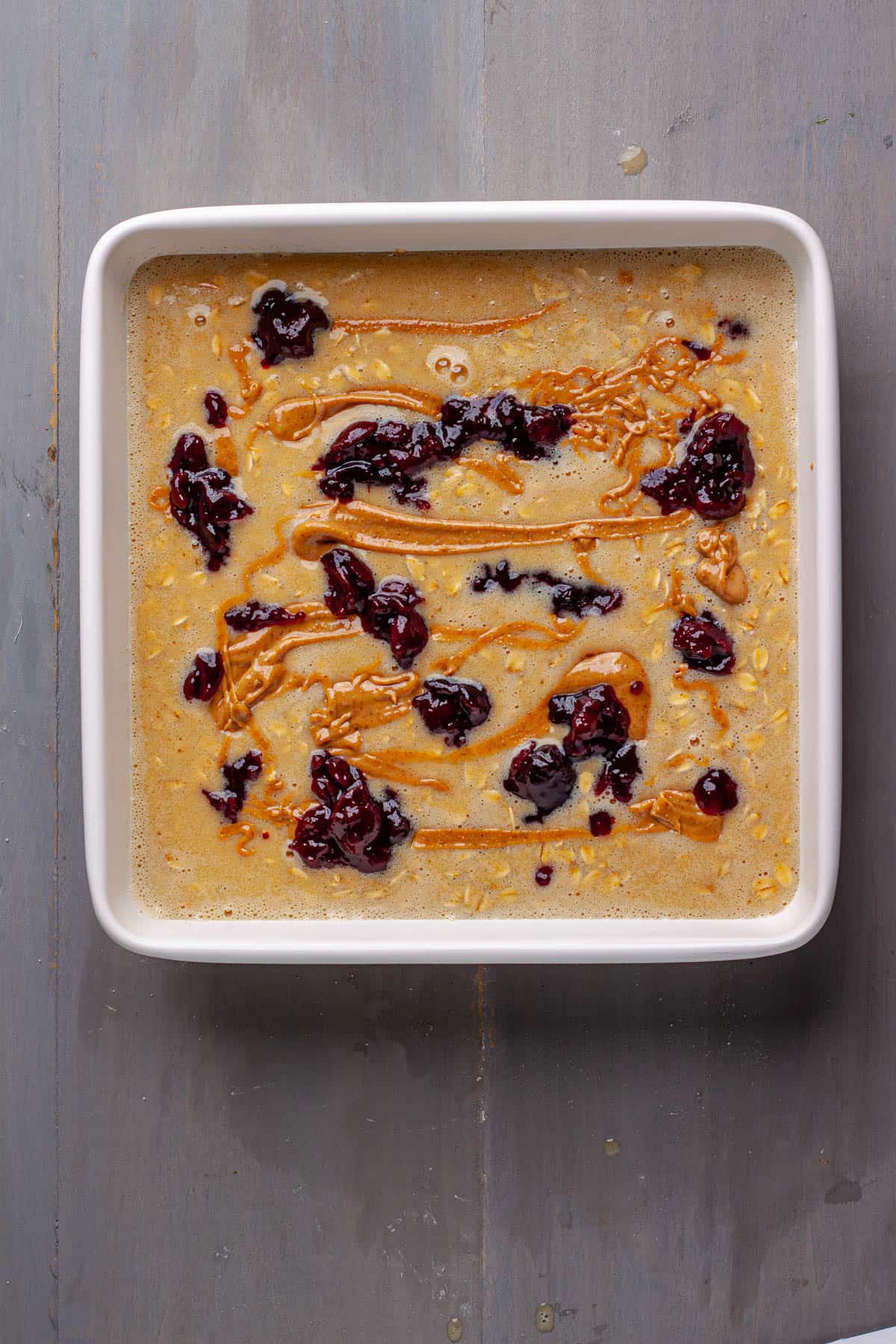 Peanut butter and jam dolloped in an uncooked baked oatmeal.